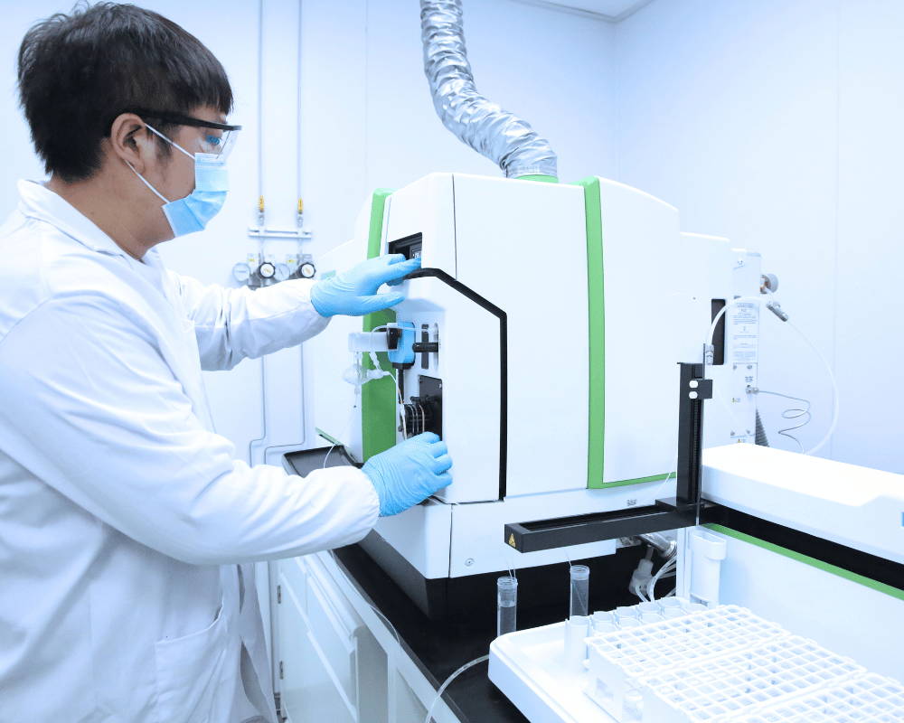 Male Apeloa scientist in lab coat using a ICP-MS in analytical laboratory following GLP.