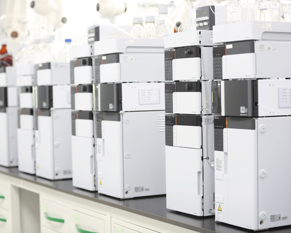 Line of white analytical instruments on a laboratory benchtop generating data for PROTAC intermediate collection.