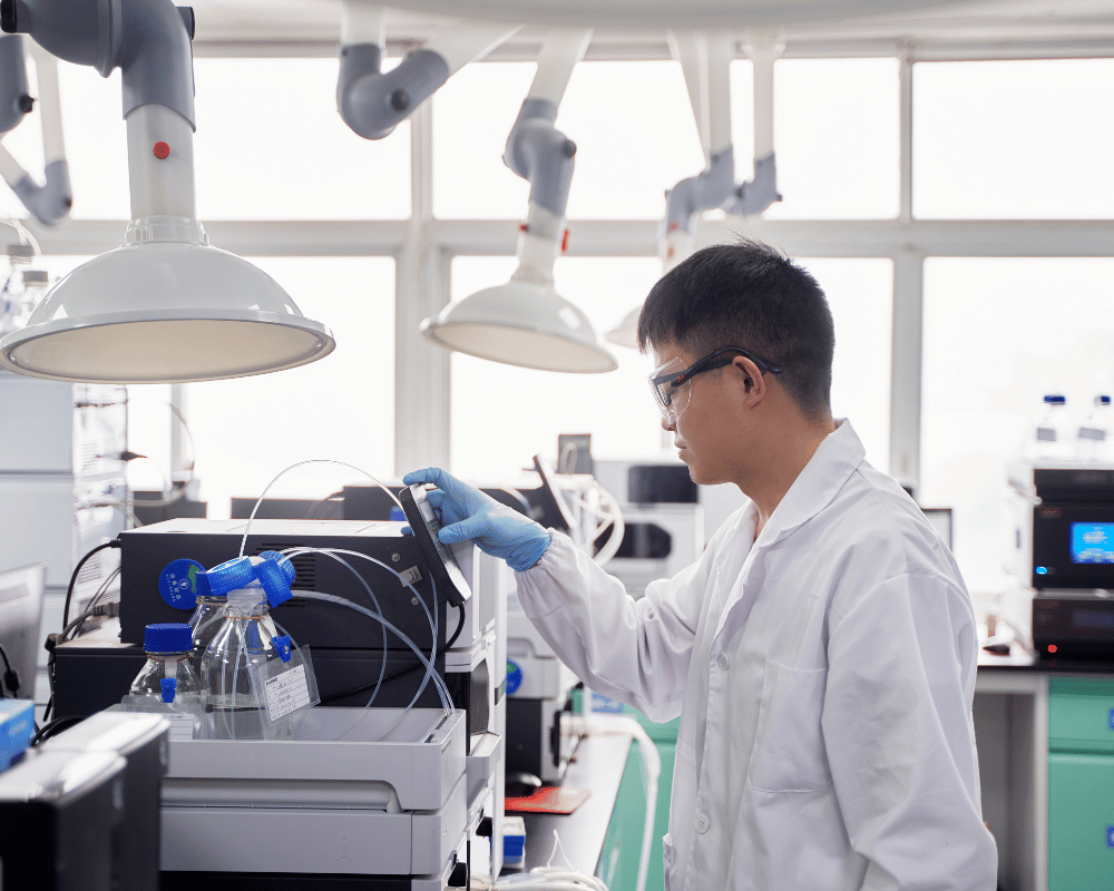 Male scientist in white lab coat working in Safety Center analytical laboratory near instruments under exhaust.