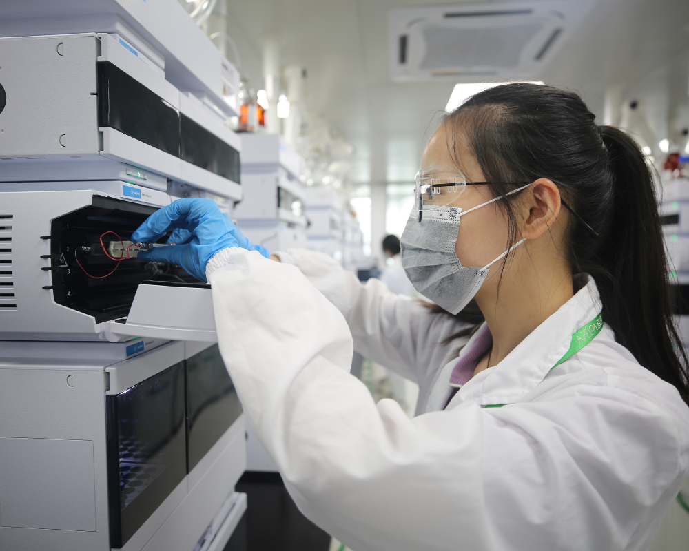 A female lab analyst loads sample vials into HPLC sample loader compartment to support ADME study analysis requirements.